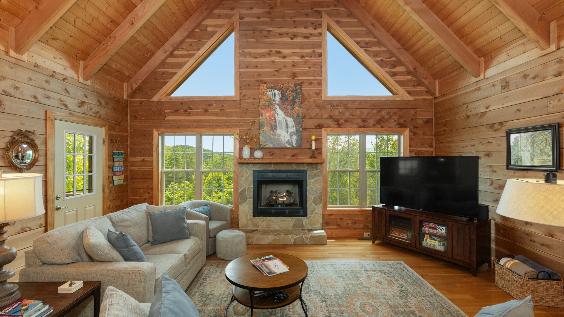 A log cabin interior with a fireplace, television, and cozy seating area.