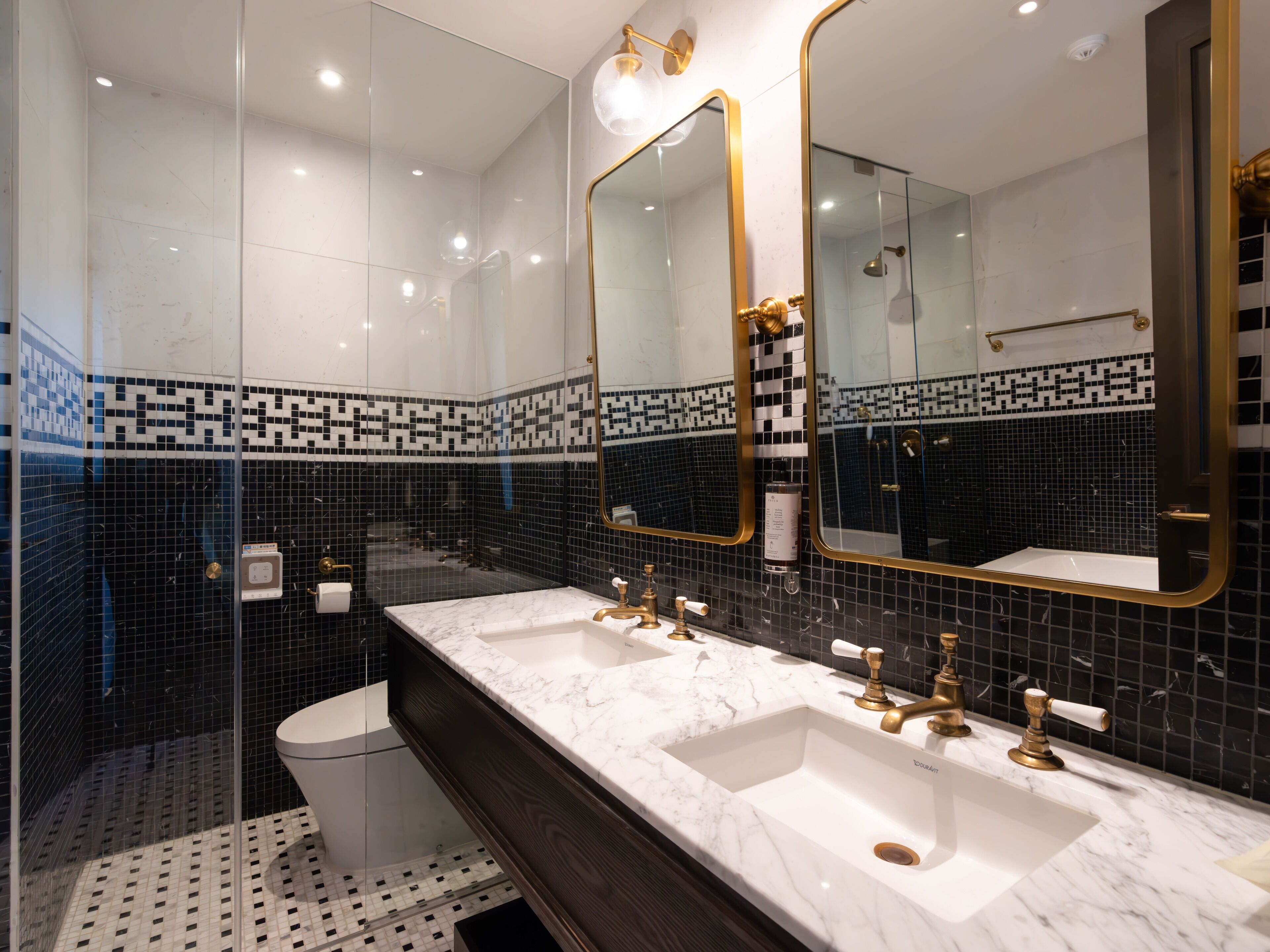 A modern bathroom with two sinks, a large mirror, and a shower area.