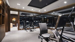 Un gimnasio con equipo de ejercicio, espejos y suelo alfombrado.