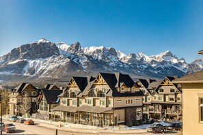 Filare di edifici in stile chalet con ampie finestre e balconi, sullo sfondo di montagne innevate.