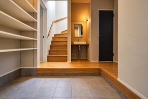 A staircase with wooden steps leading to a landing, a small sink, and a door. - TOTONOI Villa YAE (Motobu)