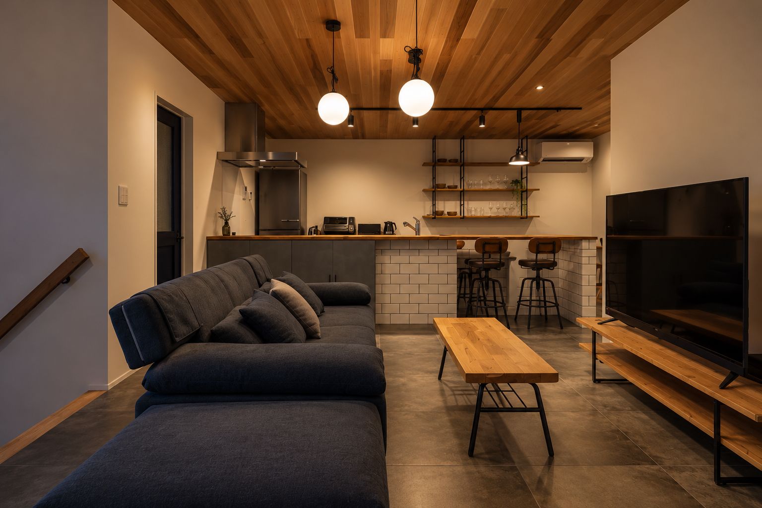 Un espace de vie moderne comprenant un canapé, une table en bois, un téléviseur et un coin cuisine avec un bar.