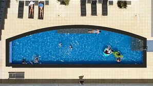 A swimming pool with people swimming and lounging.