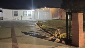 A building with a garage, a paved driveway, and a small lawn area with a fence. - Entire Newly Renovated House in North Pomona (Pomona)