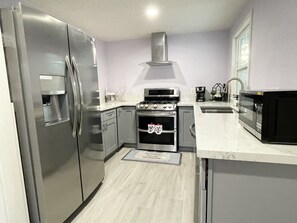 A modern kitchen with stainless steel appliances, a built-in oven, and a microwave. - Entire Newly Renovated House in North Pomona (Pomona)