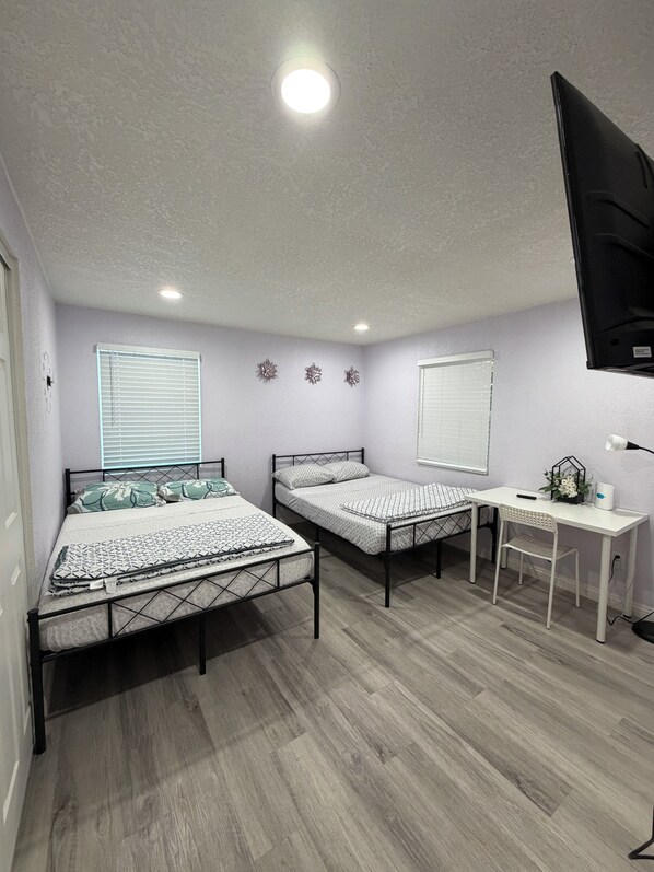 A bedroom with two beds, a desk, and a TV mounted on the wall. - Entire Newly Renovated House in North Pomona (Pomona)
