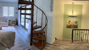 Ein Wohnzimmer mit Kamin, Fernseher, Sofa, Couchtisch und Treppe.