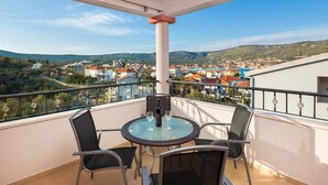 A balcony with a round table, two chairs, and a bottle of wine. - 3 - Modern apartment with garden, 80m from beach (Vinisce)