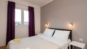 A hotel room with a bed, two bedside lamps, a nightstand, and a window with curtains. - 3 - Modern apartment with garden, 80m from beach (Vinisce)