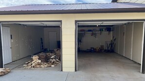A garage with two open doors, a pile of wood, and various tools and equipment inside. - 3 bedroom private vacation home in sundance (Sundance)