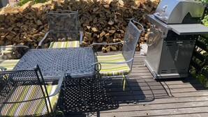 A deck with a metal table and chairs, a grill, and a stack of firewood. - 3 bedroom private vacation home in sundance (Sundance)