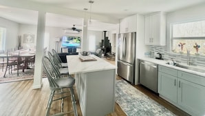 A modern kitchen with a central island, stainless steel appliances, and a dining area with a view of the outdoors.