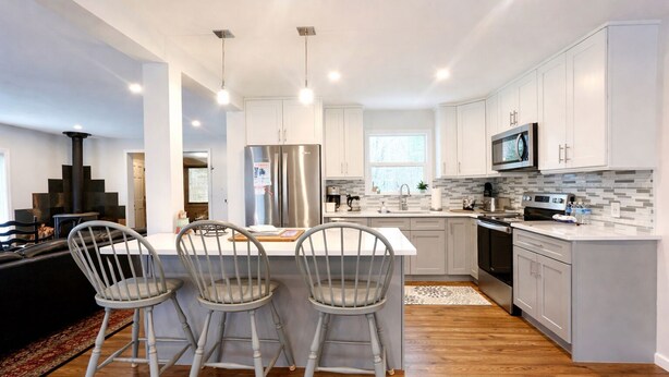 A modern kitchen with white cabinets, stainless steel appliances, and a central island with bar stools.