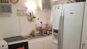 Une cuisine compacte équipée d’un lave-linge, d’un réfrigérateur, d’un four à micro-ondes et d’un évier.
