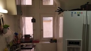 Une cuisine de taille réduite, équipée d’un réfrigérateur, d’un évier et d’une fenêtre.