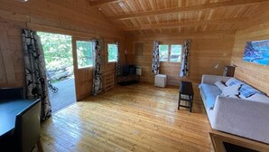 A wooden cabin interior with a sofa, a table, and a desk.