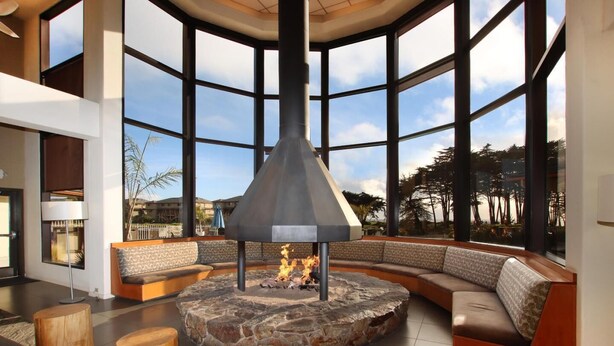 Un espace de détente moderne avec un foyer en pierre, des tabourets en bois et un aménagement de sièges incurvé.