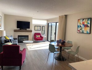 Cozy living room with a fireplace, flat-screen TV, and dining area.