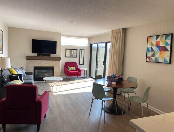 Een moderne woonkamer met een open haard, een rode fauteuil en een flatscreen televisie.