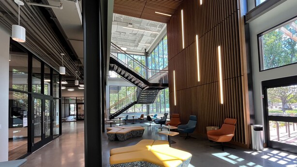 A modern interior with a staircase, seating areas, and large windows.