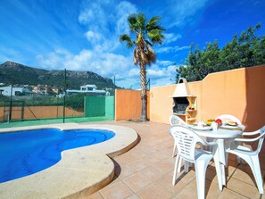A poolside area with a barbecue grill, white plastic chairs, and a table set for dining. - Solpadel by Interhome (Calpe/Calp)