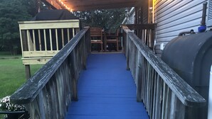 A wooden deck with blue steps leading to a covered area with string lights. - King size bedroom/ Outdoor fire pit, Game Room. Cozy getaway cottage (Cairo)