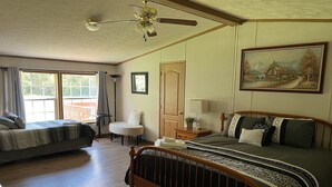 A bedroom with a large bed, a smaller bed, a chair, a desk, and a painting on the wall. - King size bedroom/ Outdoor fire pit, Game Room. Cozy getaway cottage (Cairo)