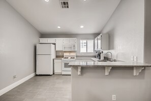 A modern kitchen with white cabinetry, a built-in oven, and a large island with a sink.