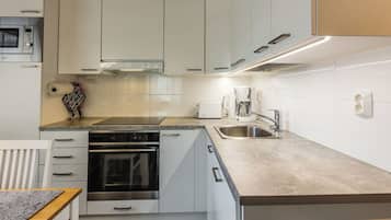 A modern kitchen with white cabinetry, a built-in oven, a stainless steel sink, and a coffee maker.