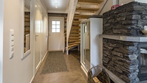 Ein Flur mit Kamin aus Stein, einer Holztreppe und einer Tür mit Fenster.