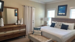 A bedroom with a bed, bedside table, lamp, and a dresser. - 3 Bedroom house in Purple Parrot (Pensacola)