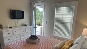 A bedroom with a bed, a TV on the wall, a dresser, and a window with blinds. - 3 Bedroom house in Purple Parrot (Pensacola)