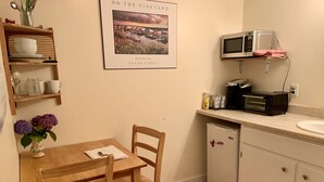 Une petite cuisine avec une table en bois, des chaises, un four à micro-ondes, un grille-pain et un évier.