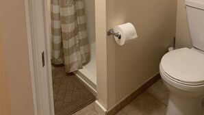Une salle de bain équipée de toilettes, d’un rideau de douche et d’un porte-rouleau de papier toilette.