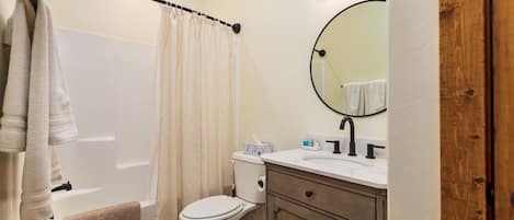 Un baño con bañera, inodoro y tocador con espejo.