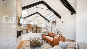 A spacious living room with a high ceiling, a staircase, and a large window providing natural light. - Luxury in Old Town, Walk to Main St. and Town Lift, Forever Views!

 (Park City)