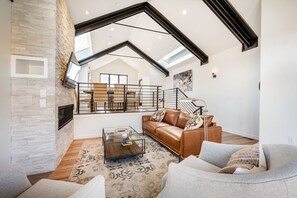 A spacious living room with a high ceiling, a staircase, and a large window providing natural light. - Luxury in Old Town, Walk to Main St. and Town Lift, Forever Views!

 (Park City)