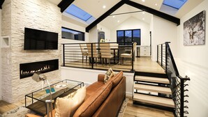 A spacious living area with a fireplace, a glass coffee table, and a brown sofa. There is a staircase with a black railing leading to an upper level. - Luxury in Old Town, Walk to Main St. and Town Lift, Forever Views!

 (Park City)