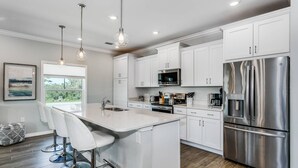 A modern kitchen with white cabinets, stainless steel appliances, and pendant lighting. - Winter Monthly Available | Golf Cart Included | Pet Friendly | Beach Club | Free Golf |Pools |Tennis (Pensacola)