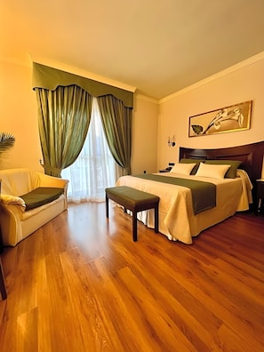 A hotel room with a bed, a bench, a sofa, and a painting on the wall. - Los Dolmenes (Antequera)