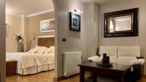 A hotel room with a bed, a sofa, a coffee table, and a mirror. - Los Dolmenes (Antequera)