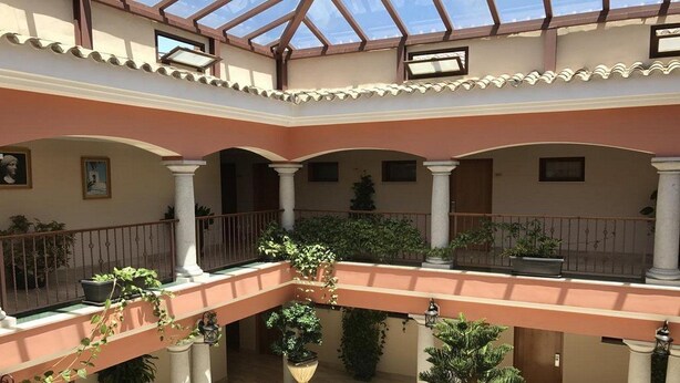 A multi-level atrium with a glass ceiling, columns, and potted plants. - Los Dolmenes (Antequera)