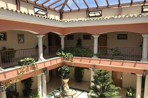 A multi-level atrium with a glass ceiling, columns, and potted plants. - Los Dolmenes (Antequera)