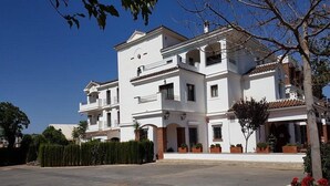 A multi-story white building with balconies and a covered driveway. - Los Dolmenes (Antequera)