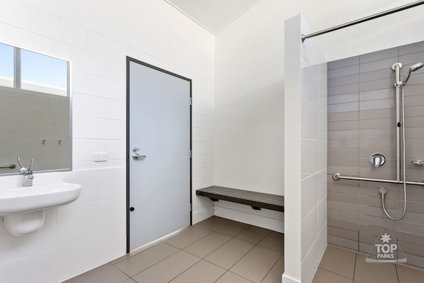 A modern bathroom with a white sink, a door, and a shower area with a glass door.