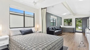 Une chambre moderne avec un grand lit, un canapé, un bureau et une fenêtre donnant sur l’extérieur.