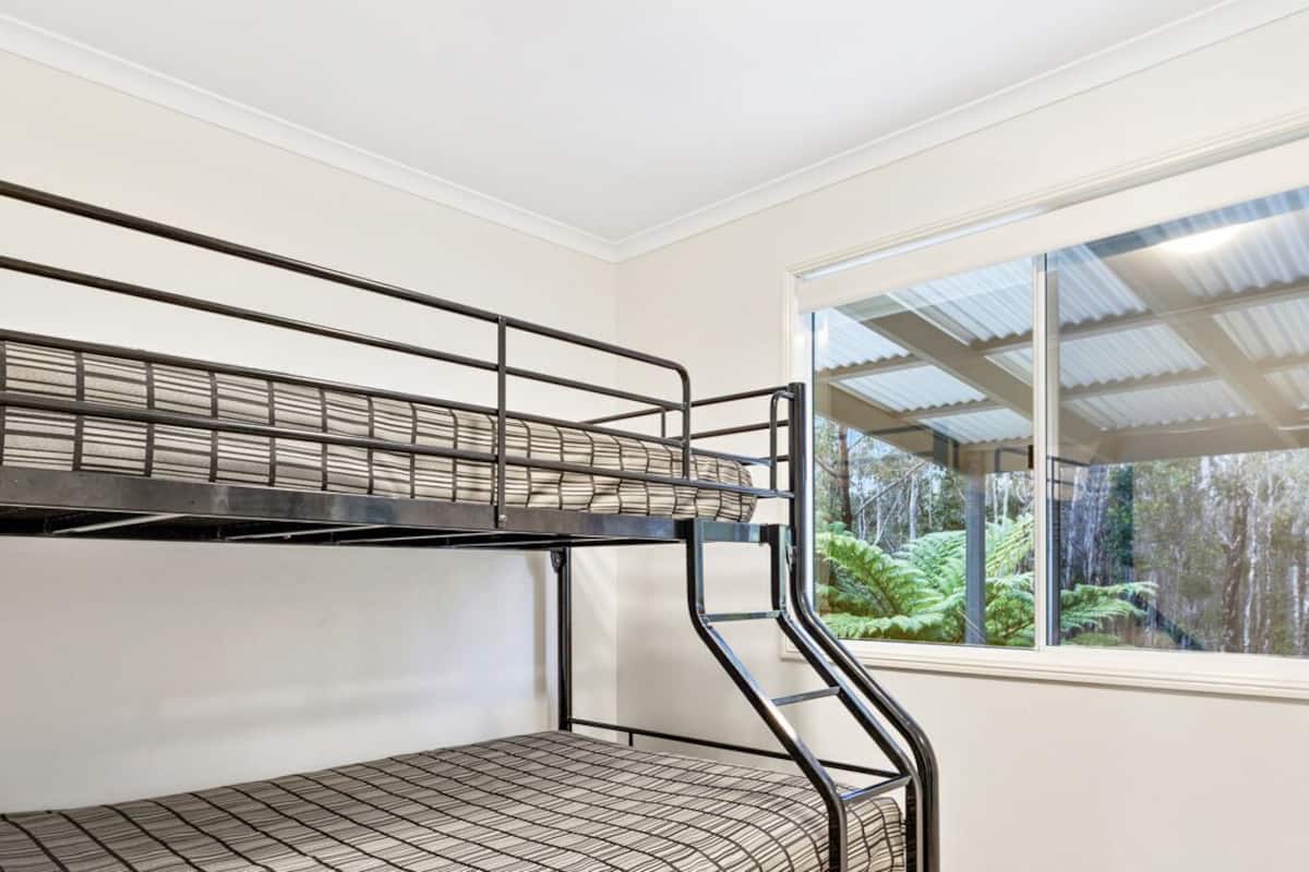 Dormitorio con literas y ventana que ofrece vistas a árboles.