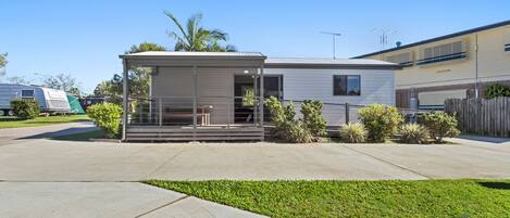 A single-story mobile home with a covered porch and a small garden area.