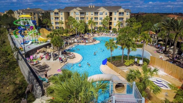 A resort with a large pool, palm trees, and a water park.
