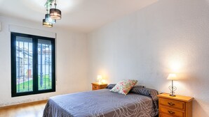 Een slaapkamer met een bed, twee nachtkastjes met lampen, een raam met uitzicht en een deur.